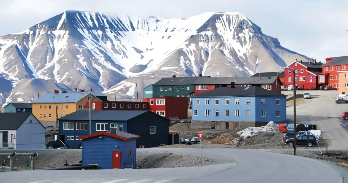 Painted timber buildings in central Longyearbyen below a snow-covered mountain