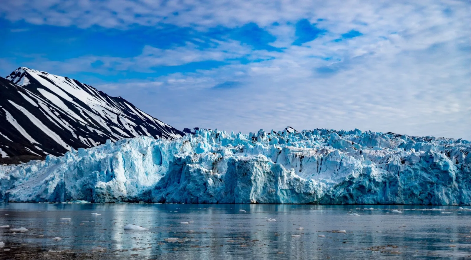 Blue calving face of a Svalbard tidewater glacier under a bright sky