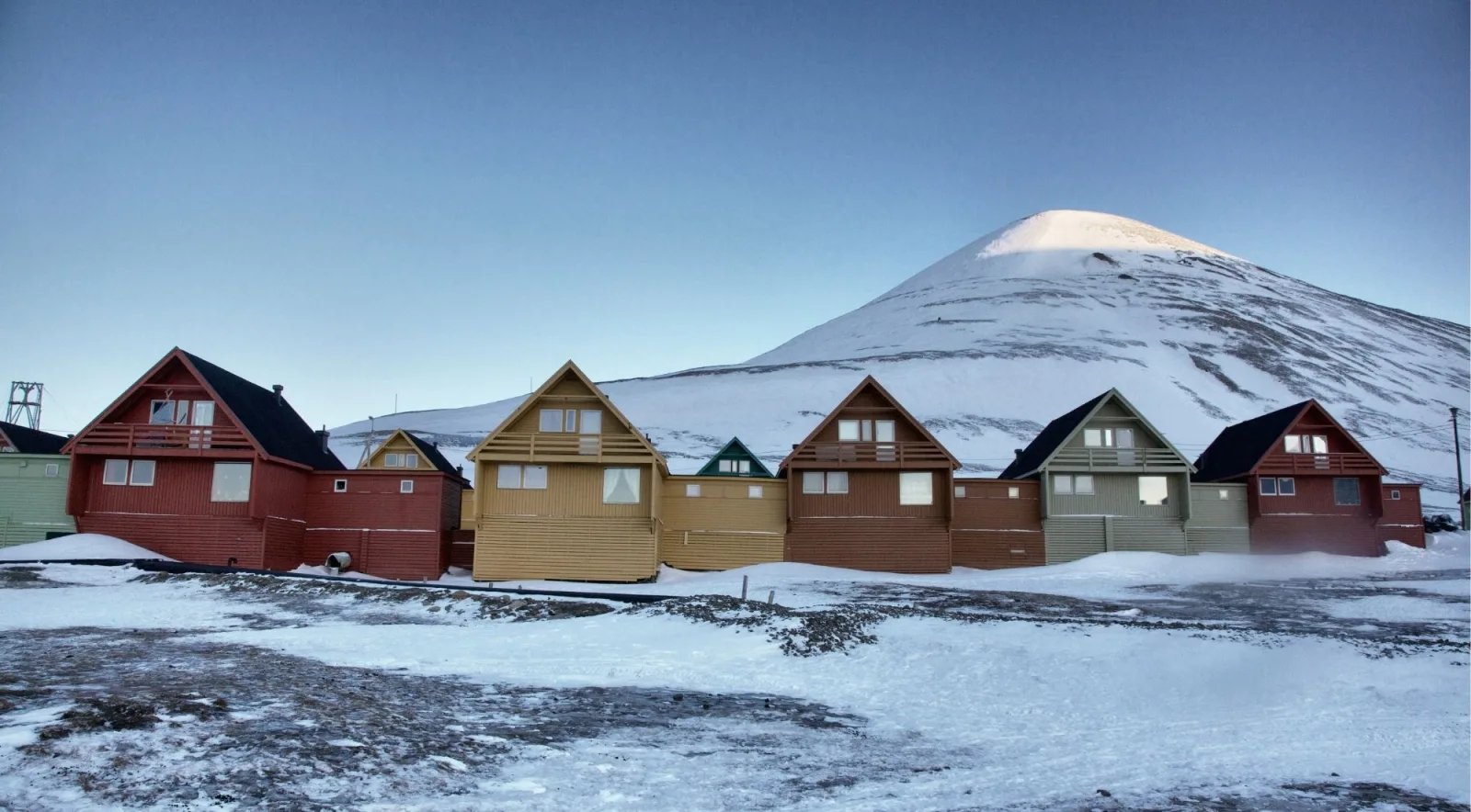 Row of coloured A-frame houses in Longyearbyen below Sukkertoppen at winter dusk