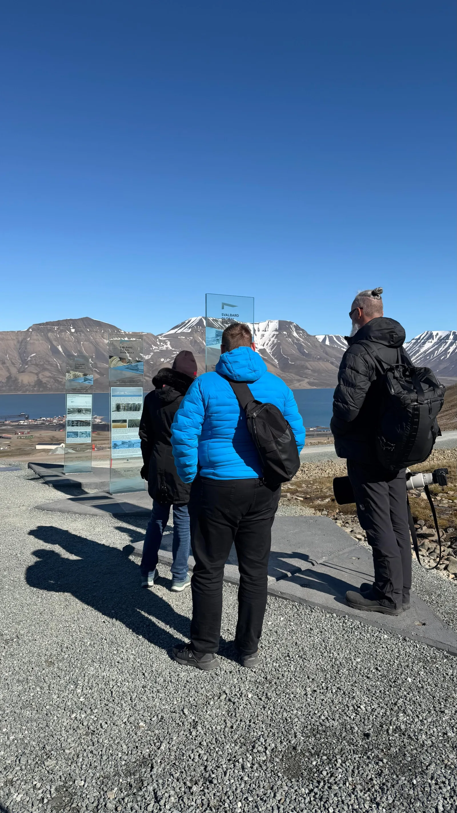 Group reading the Seed Vault information panels with Adventfjorden and the mountains behind