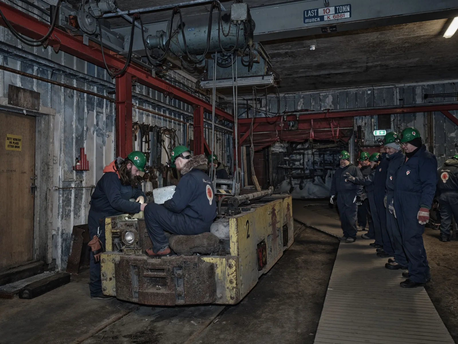 Guides demonstrating a yellow battery locomotive to a group in the Gruve 3 engine hall