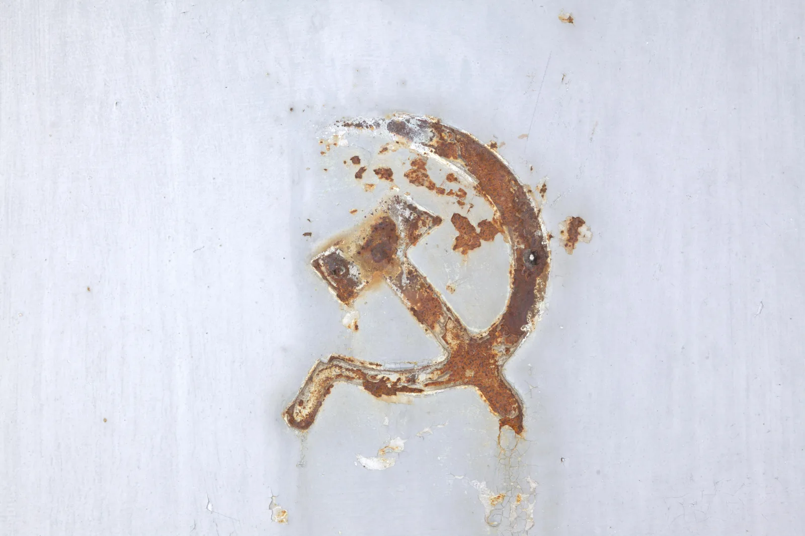 A rusting hammer-and-sickle emblem on a painted metal door in Pyramiden