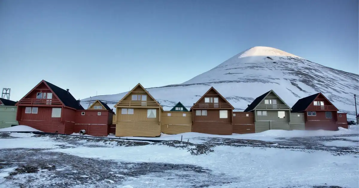 Row of colourful A-frame houses in central Longyearbyen below a snowy peak