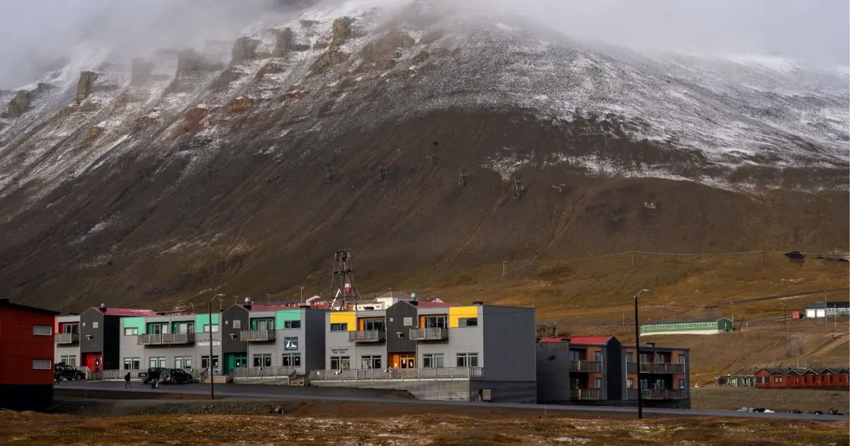 Modern apartment blocks in Longyearbyen below a dark mountain slope